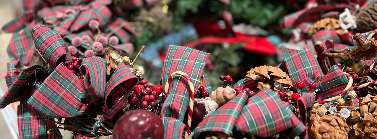 A holiday wreath with plaid ribbon, berries, and pinecones